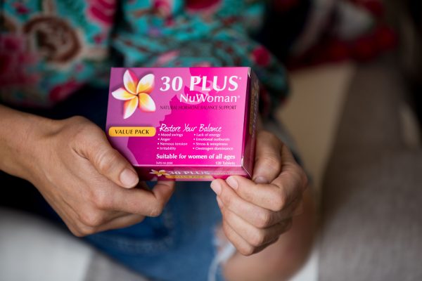 A lady holding a box of 30 PLUS NuWoman